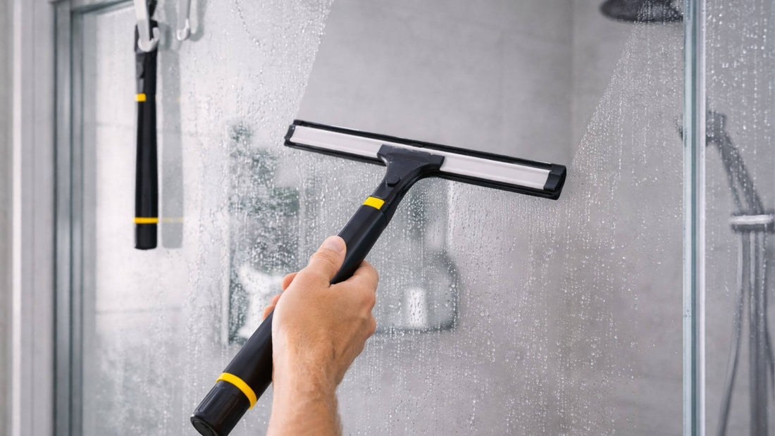 Raclette vitre de douche nettoyant une paroi en verre pour enlever l’eau et éviter les traces après la douche